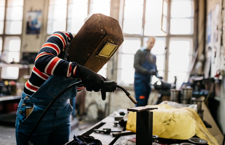 Female apprentice welder working in a workshop.