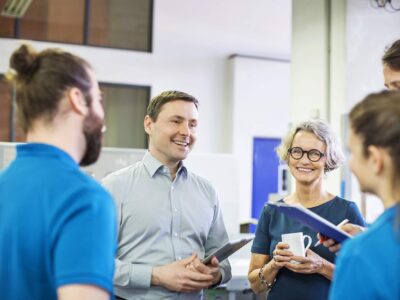 Happy manager meeting with workers in printing factory Happy manager meeting with workers in printing factory. Businessman having a discussion with coworkers in printing plant.