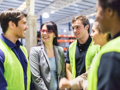 Shape WA's workforce by joining the Industry Training Council Board Team of workers having a meeting in warehouse. Female warehouse manager talking with workers.